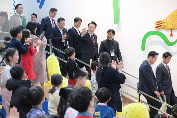 윤석열 대통령이 '국립어린이박물관 개관식'에 참석하기 위해 어린이들에게 손을 흔드며 계단에서 내려오고 있다