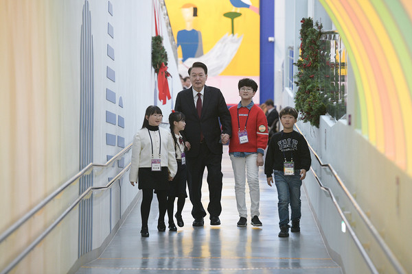 윤석열 대통령이 어린이들과 함께 손 잡고 걸어오고 있다.